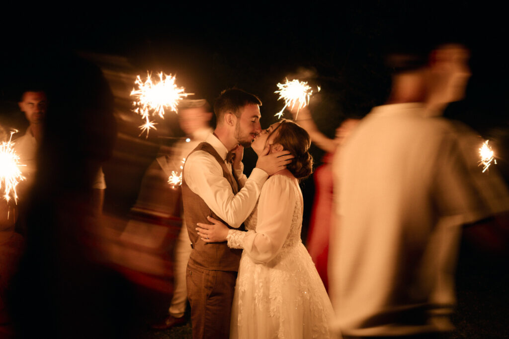Deux mariés s'embrassent à la lueur de cierges magiques.
